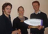 Debbie Flood being presented the commemorative oar by John Amery and Tom Van der Gucht