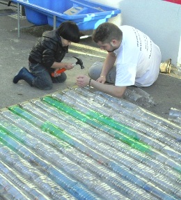 Undergraduate David Stoddern helps a younger volunteer building a greenhouse