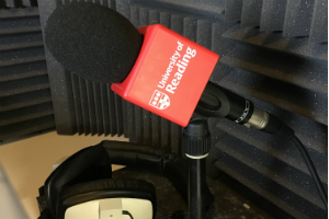 A microphone in a radio booth with a University of Reading logo