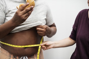 Man having waist measured while eating burger