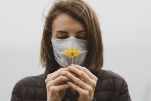Woman wearing mask tries to smell a flower
