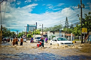 A city scene with people making their way through floods