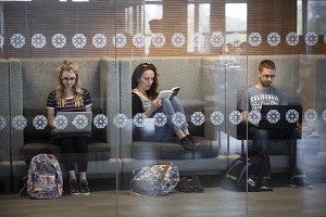 Three students sitting in a study space reading and working