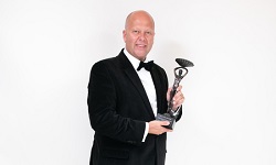 colour photograph of campus commerce director Matt White holding Catey award