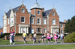 Colour photograph of marathon runners, red brick victorian building to background